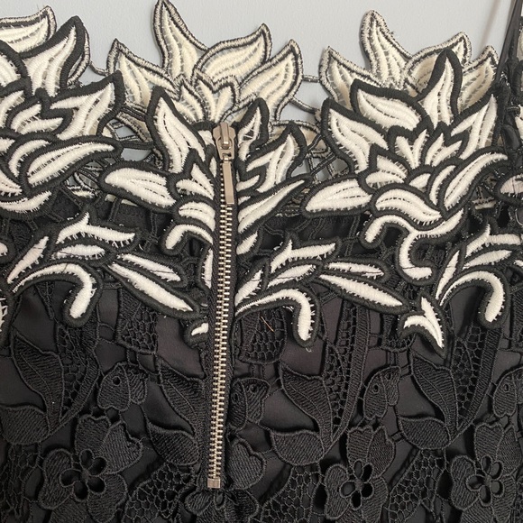 It’s a black and white off shoulder top with an embroidered flower design. - Picture 4 of 7